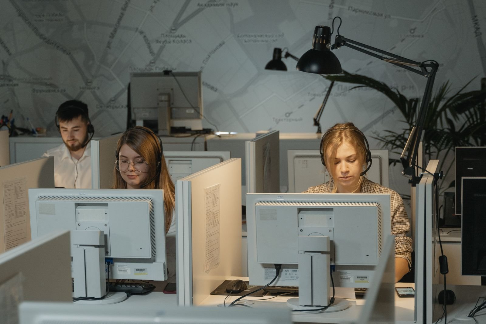 Real call center specialists working at office desks with headsets