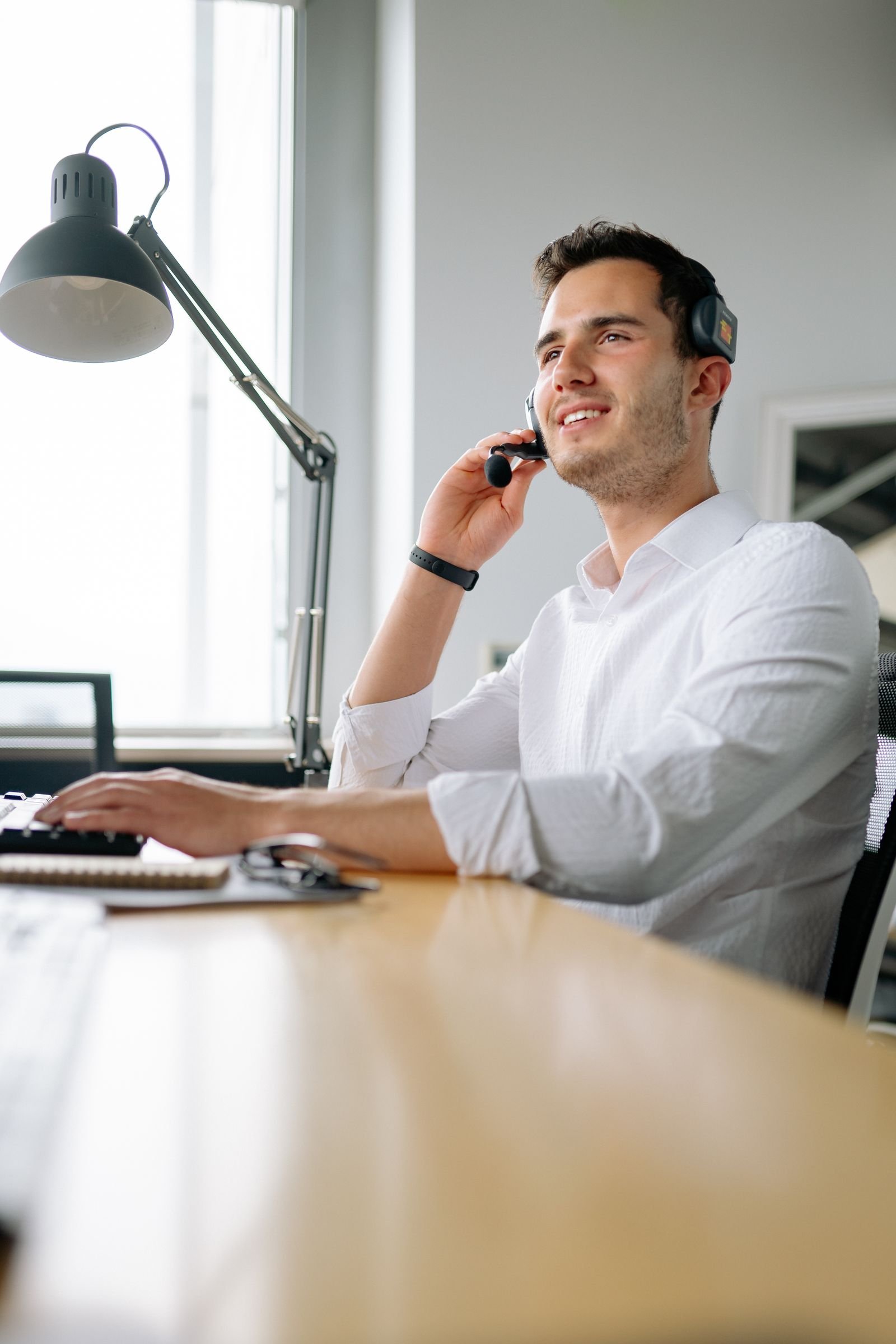 Real office worker using a headset while typing at a workstation