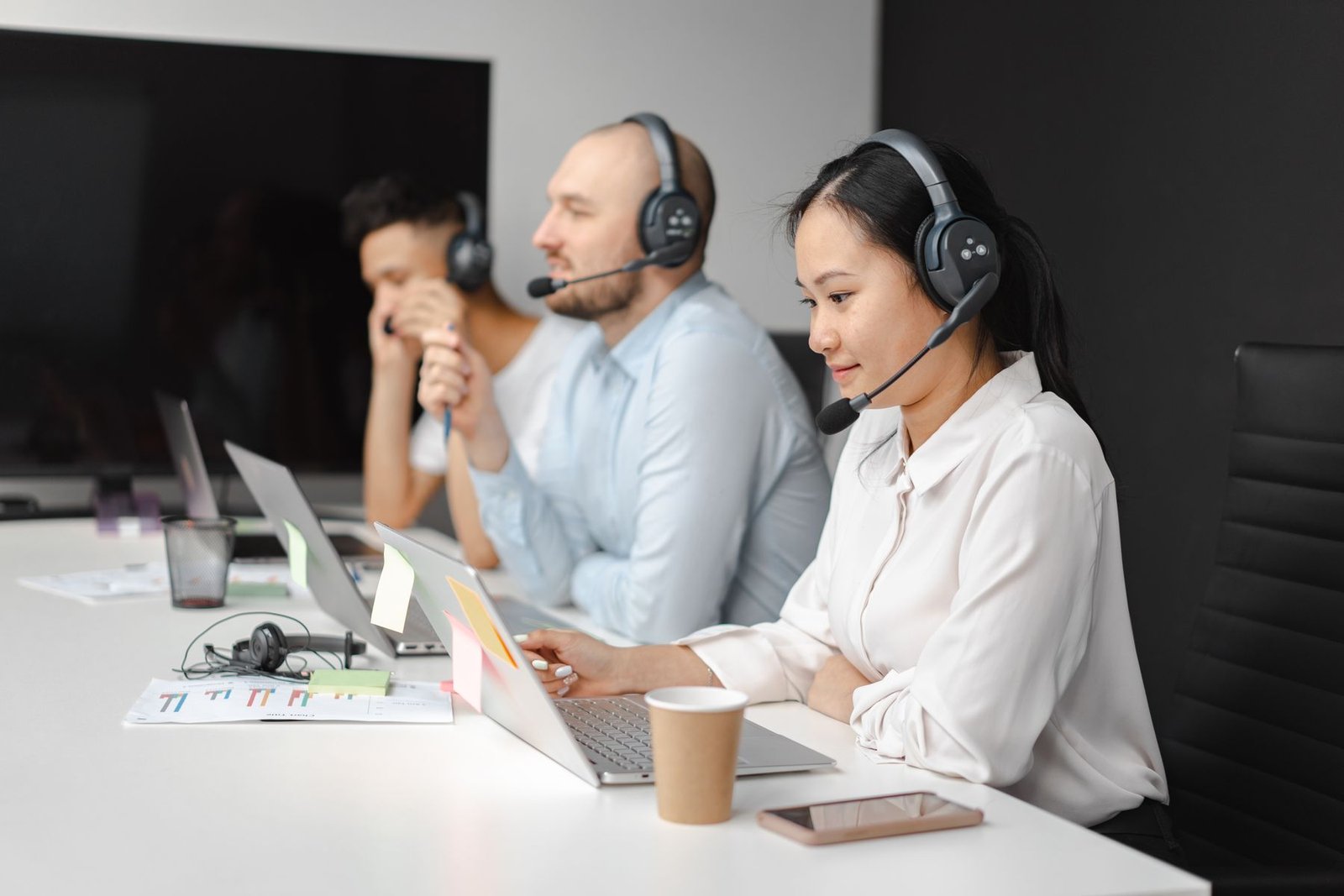 Real customer support team wearing headsets and working with laptops