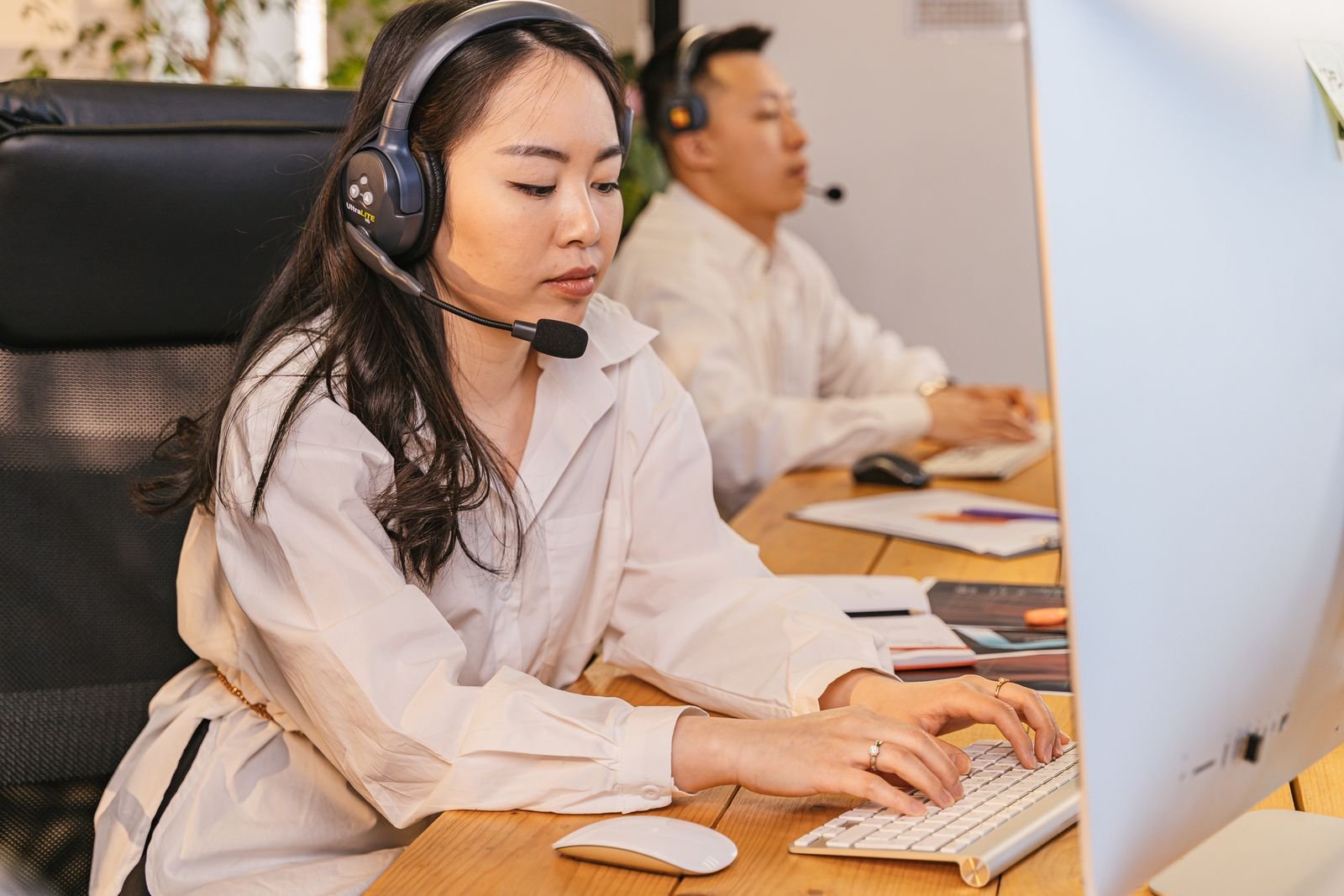 Real customer support professionals working at computers with headsets